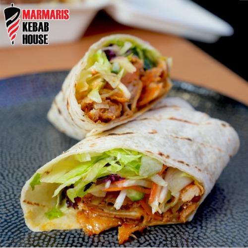 Marmaris Kebab House chicken wrap, sliced in half, sits on a dark plate.